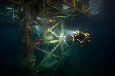 Underwater drone inspecting the submerged structure of an offshore oil platform in the North Sea